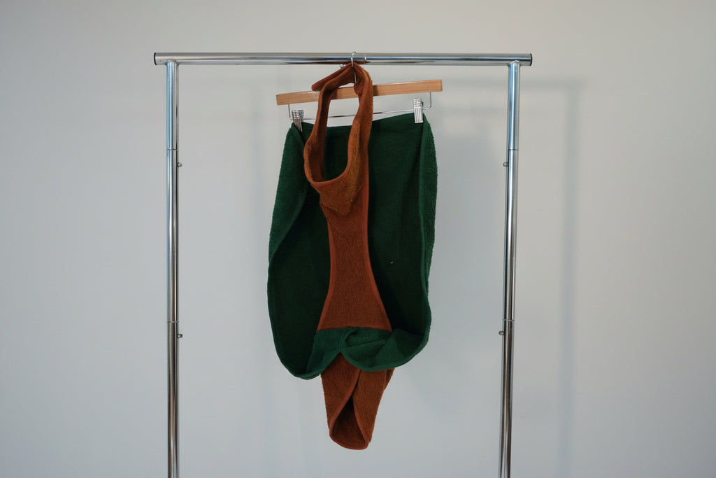 Green and brown garment on a hanger against a white background